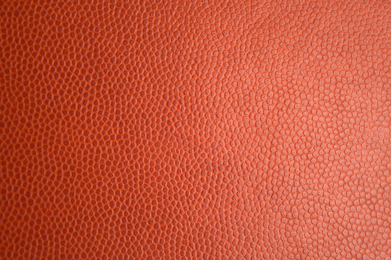 Detailed macro photo of orange leather texture, perfect for backgrounds or materials.